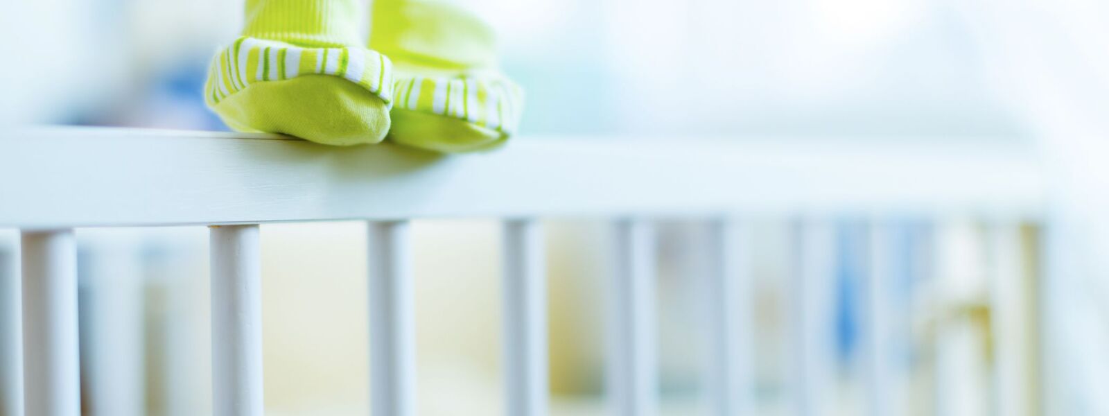 Baby shoes on the edge of a cot Baby shoes on the edge of a cot.