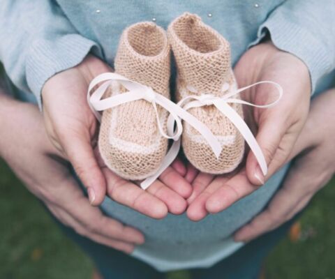 Couple holding baby booties in hands (Demo) Couple holding baby booties in hands (Demo)